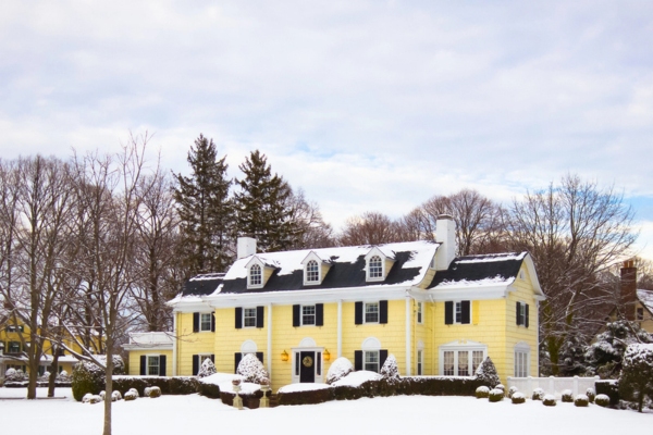 big yellow house covered in snow depicting heating oil consumption based on home size