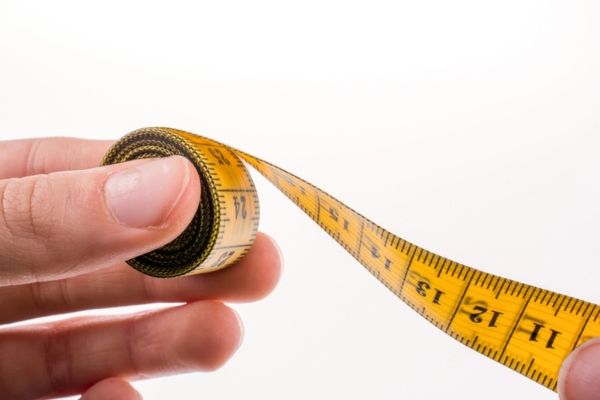 Person holding yellow measuring tape depicting sizing a generator