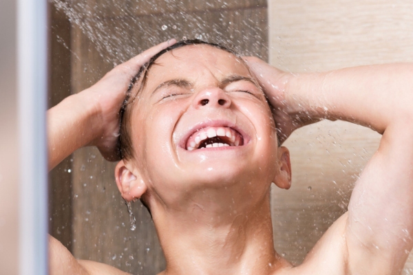 cheerful boy taking a cold shower to beat the summer heat