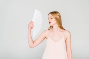 woman keeping cool during summer with a hand fan