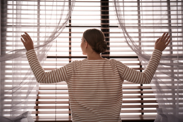 woman opening window to let cool air in from outside