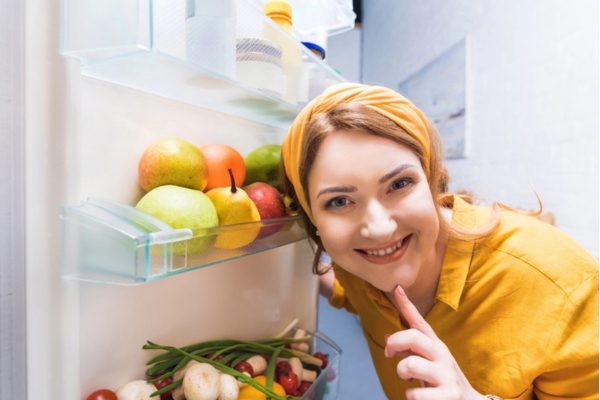 woman smiling while checking her running fridge despite power outage