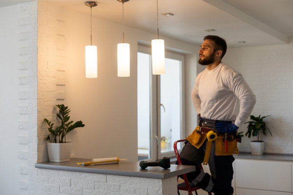 electrician examining home lights depicting signs of a larger AC issue