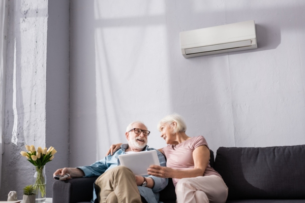 senior couple lounging at the living room keeping cool with a dutless air conditioner