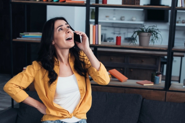 woman on the phone while looking at lights flickering when AC turns on