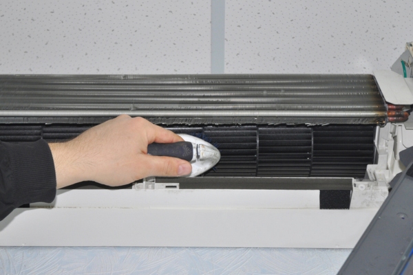 homeowner cleaning air conditioner with brush