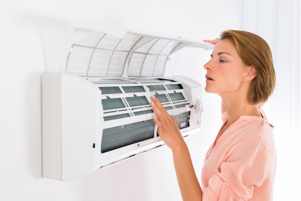 woman assessing and listening to ductless air conditioner at home