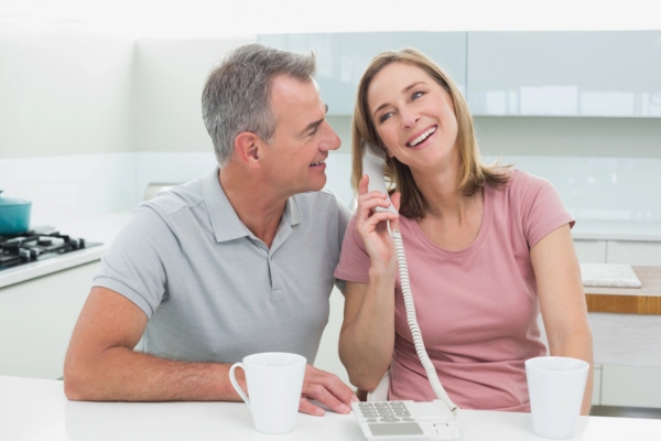 couple calling a furnace repair company using the phone in the kitchen