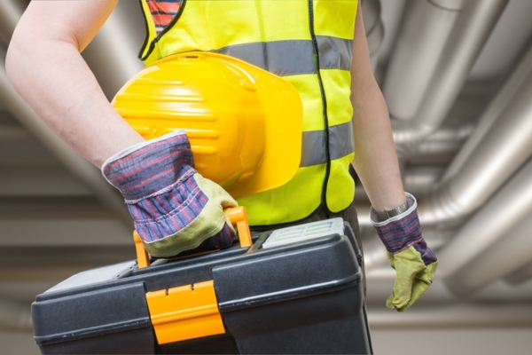 cropped view of a contractor and his tools with image of HVAC ductwork behind him