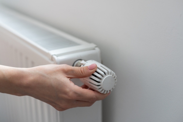 cropped view of a person's hand turning on home radiator to an oil heating system