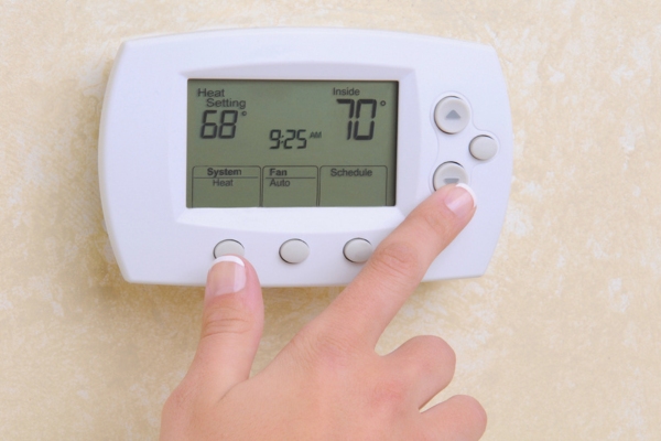 close-up of a woman's hand adjusting home thermostat