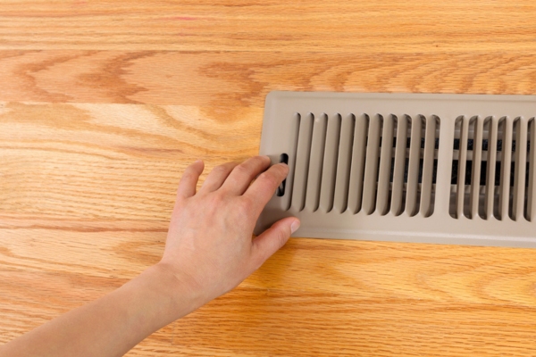 cropped view of a woman's hand opening floor vent depicting forced air systems