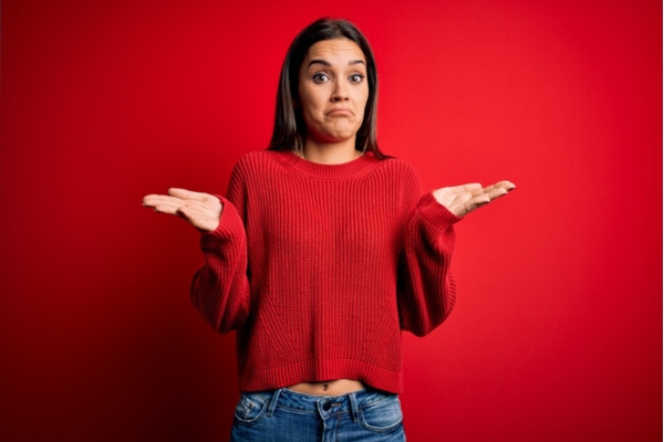 woman wearing a red sweater with both hands open depicting comparison between forced air and hydronic heating systems