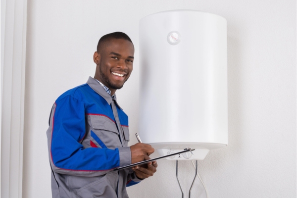 HVAC professional holding a clipboard by a boiler calculating heat loss