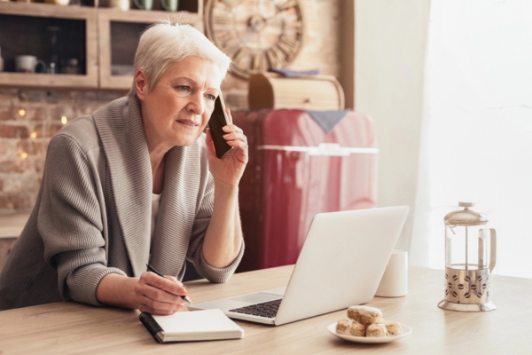 woman looking at laptop while calling for oil delivery at home