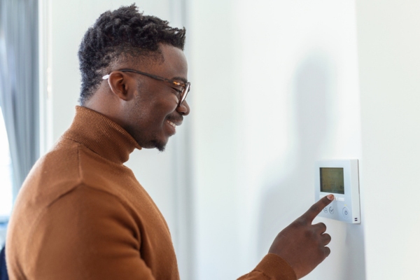 man adjusting thermostat for home heating oil efficiency